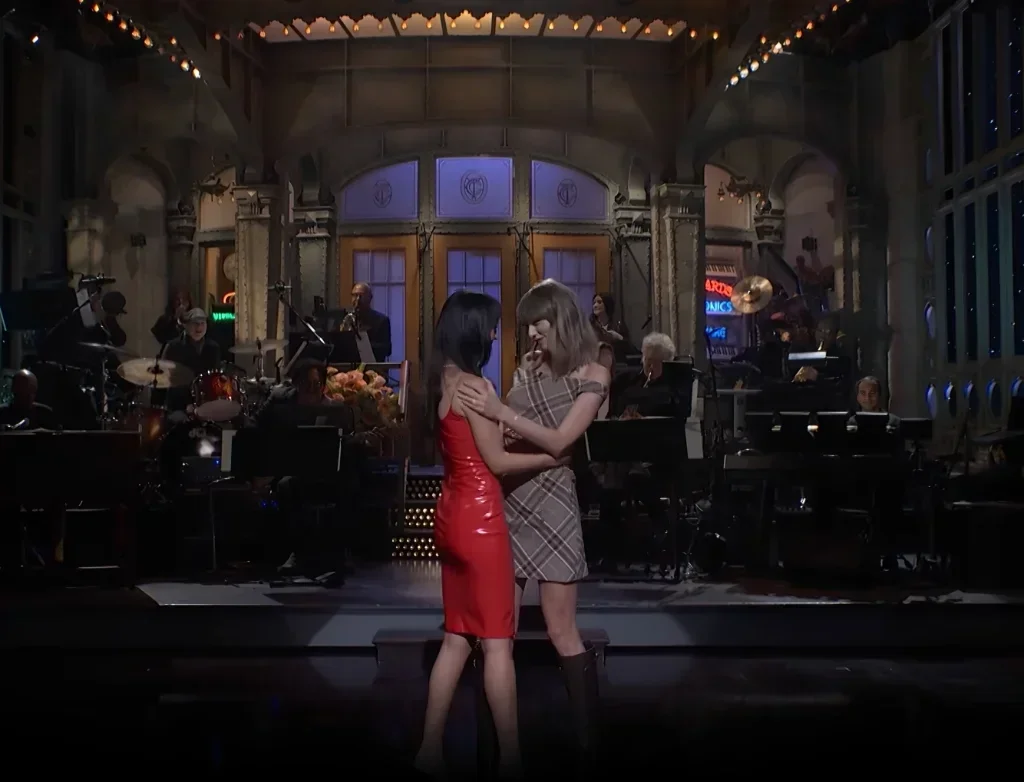 Taylor Swift and Dakota Johnson embrace on the Studio 8H stage
