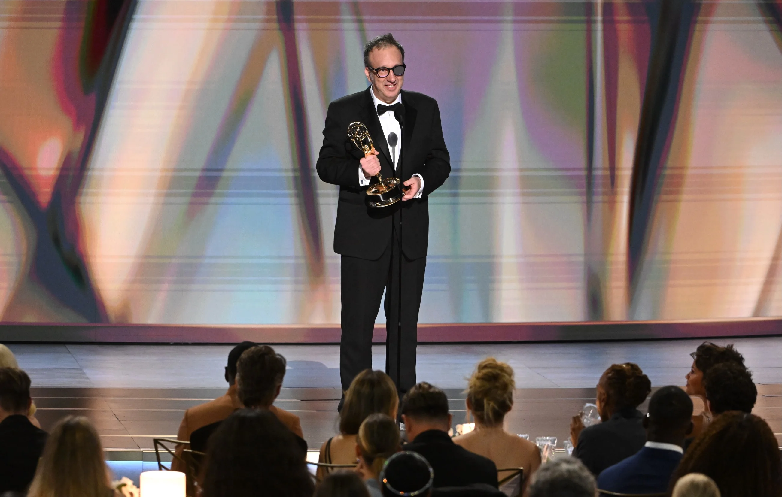Saul Metzstein wearing statement tortoiseshell glasses and black tuxedo