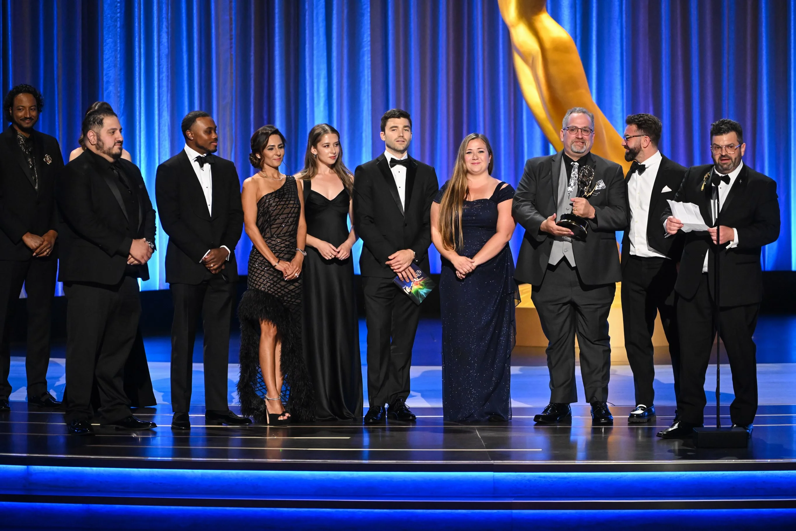 Cast members locked in an emotional group embrace on stage