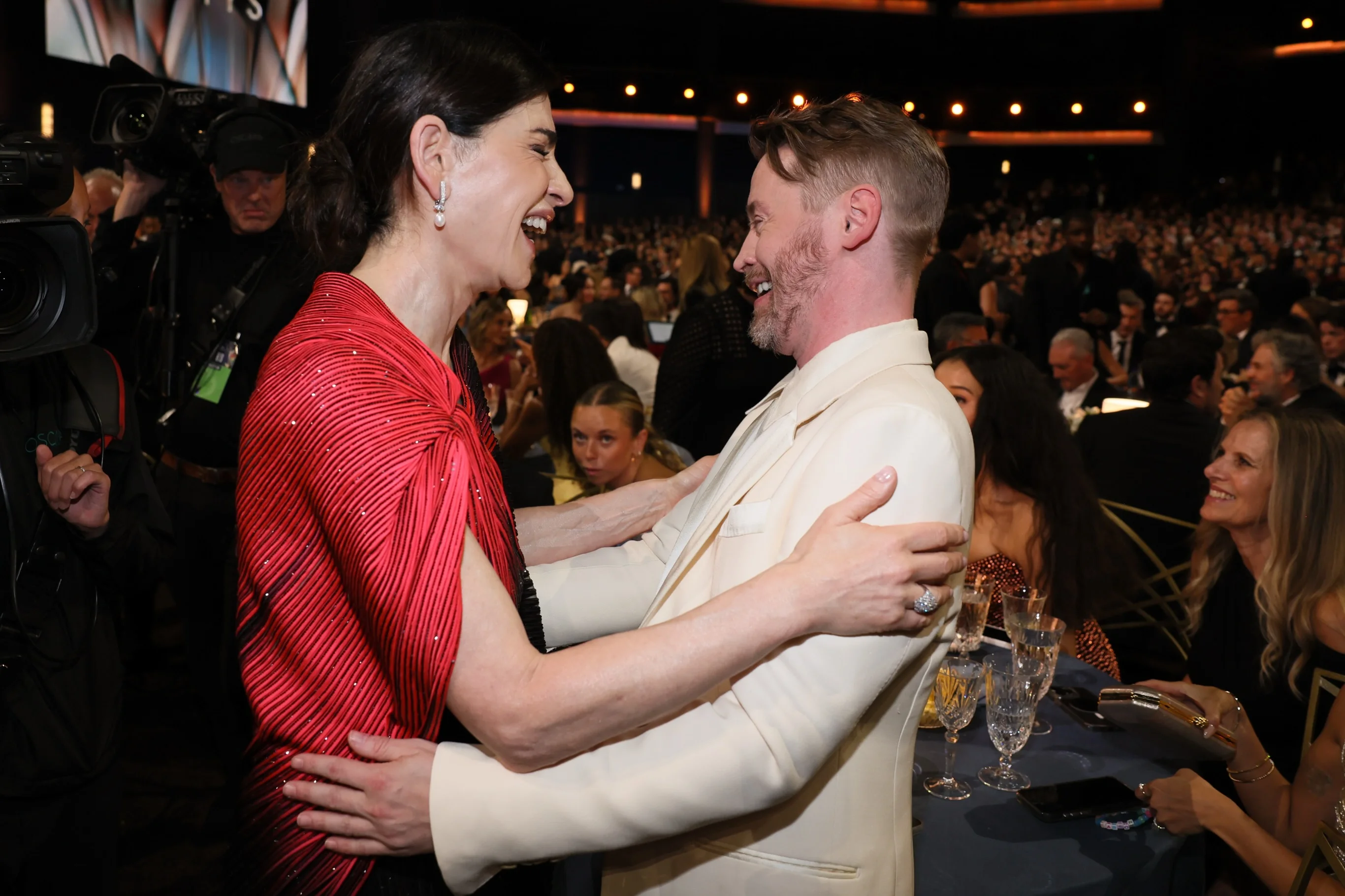 Two stars embracing tenderly at a dining table during the broadcast