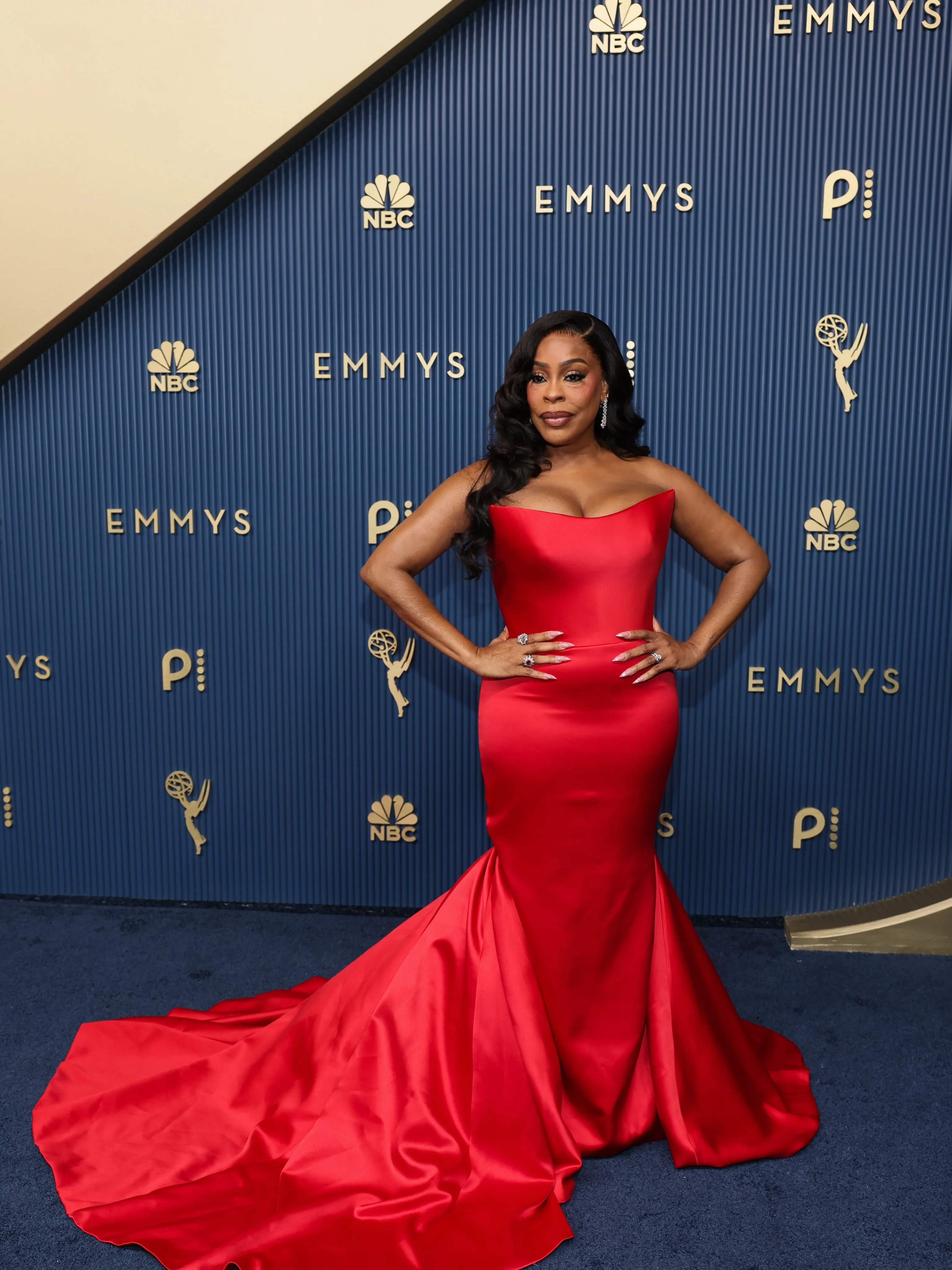 Golden Brooks in crimson red mermaid gown with dramatic sweeping skirt