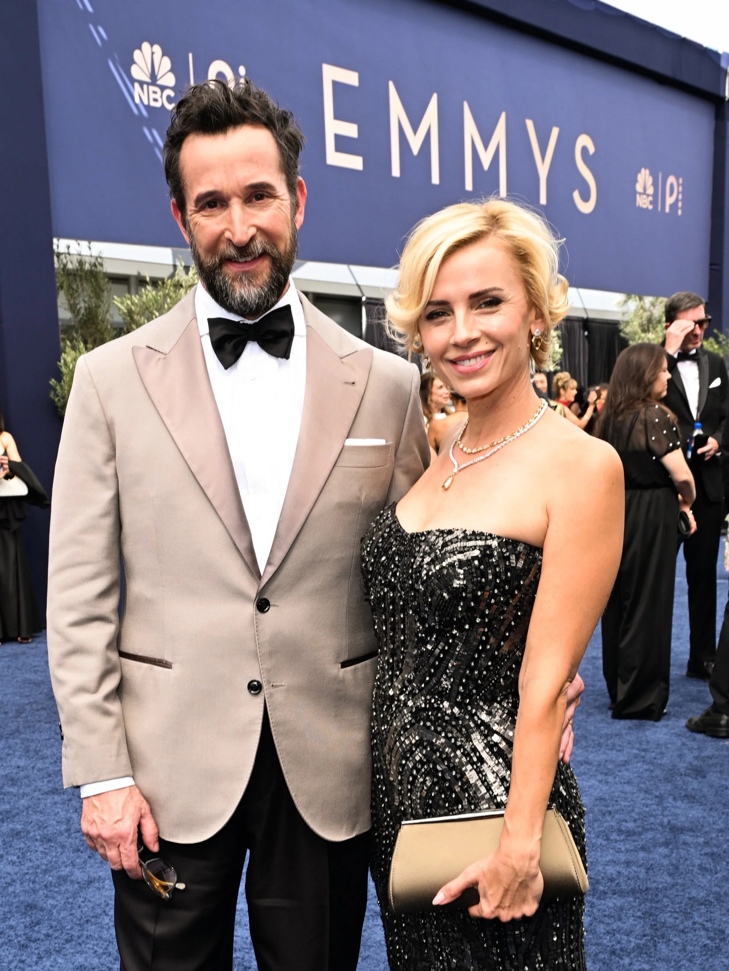 Noah Wyle in taupe tuxedo and Sara Wells in strapless black gown on red carpet