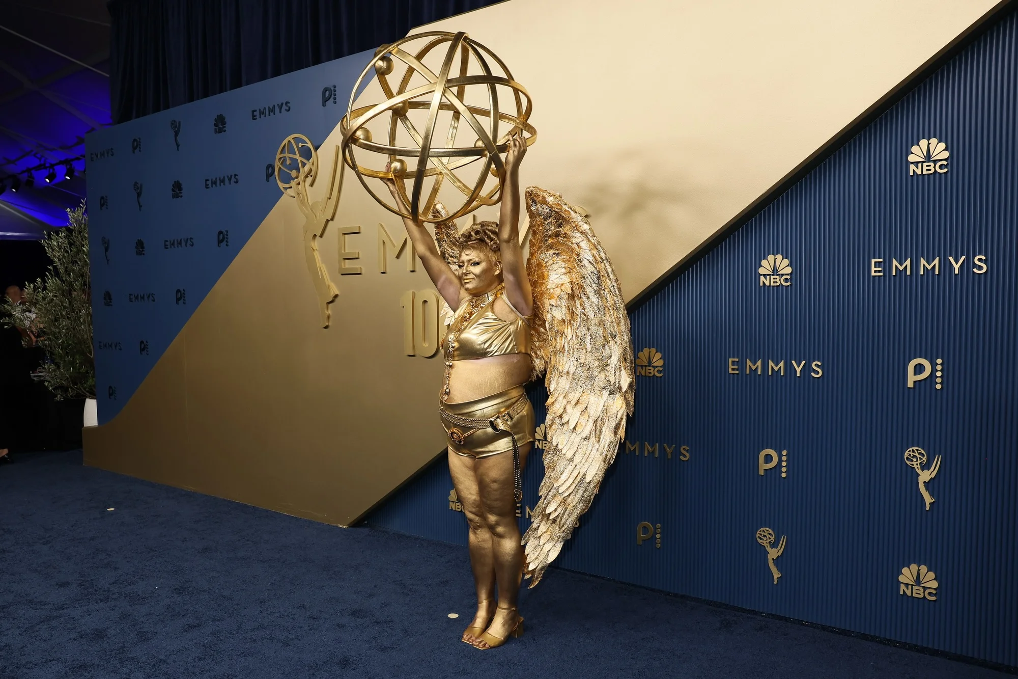 Oversized golden Emmy statuette sculpture standing illuminated backstage