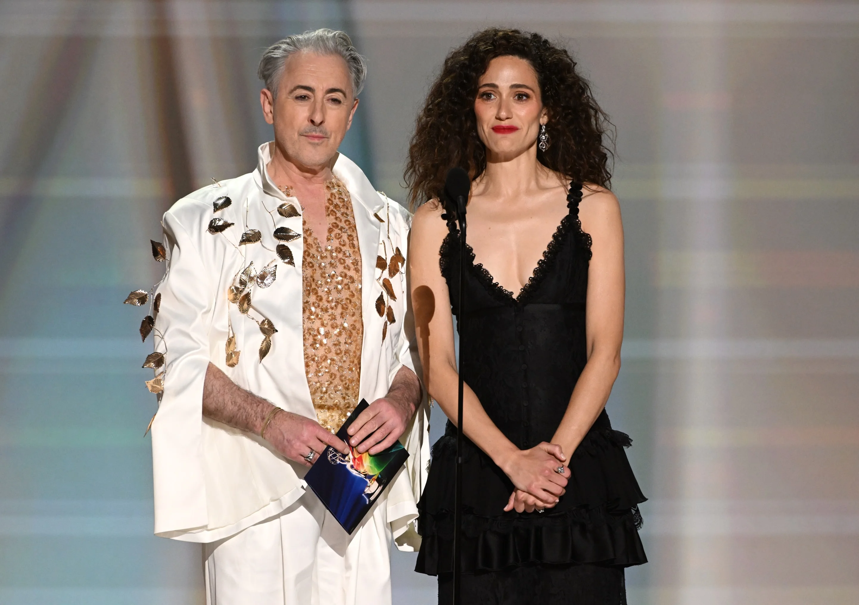 Alan Cumming and guest posing in botanical and ruffle-adorned eveningwear