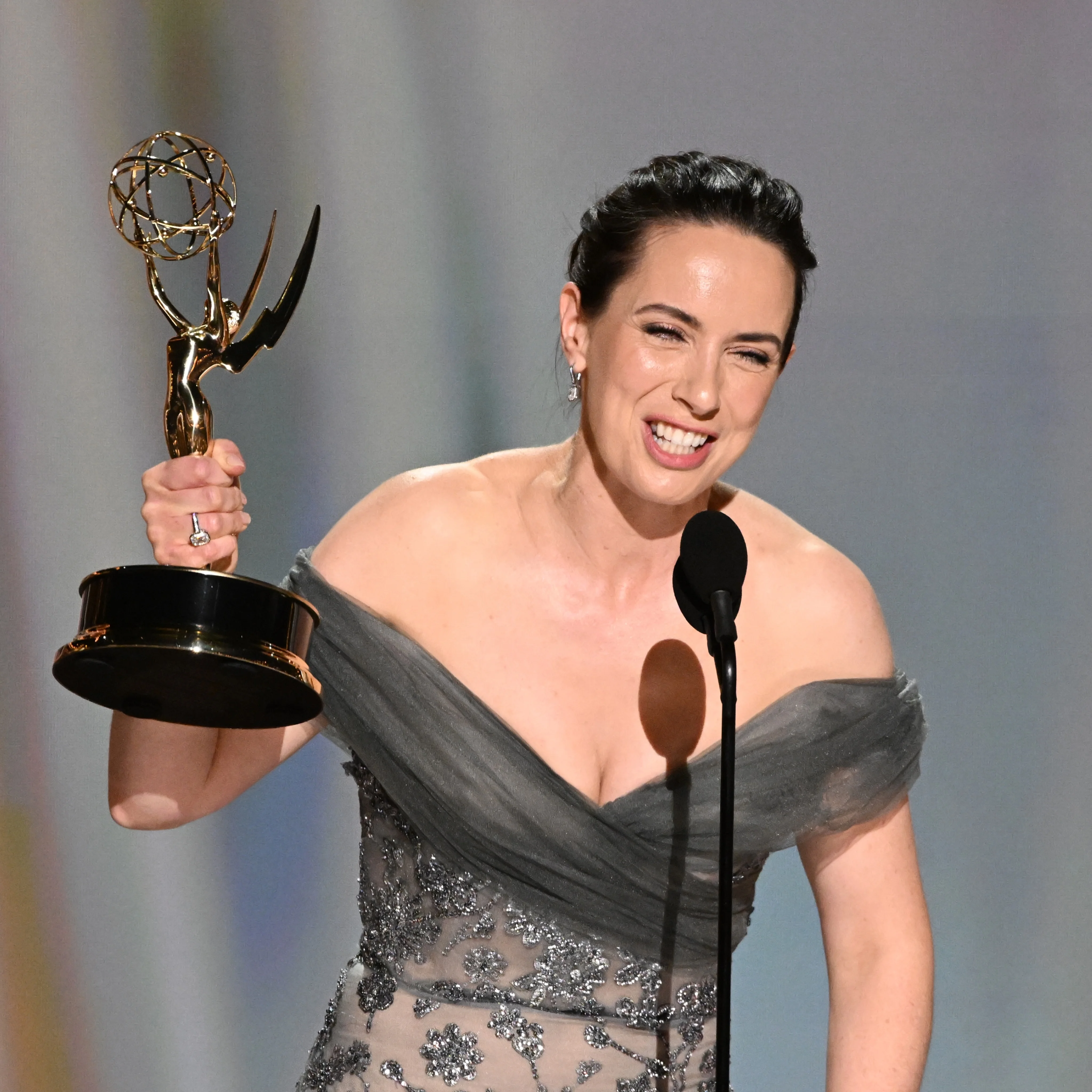 Winner holding Emmy aloft at the microphone beaming with pride