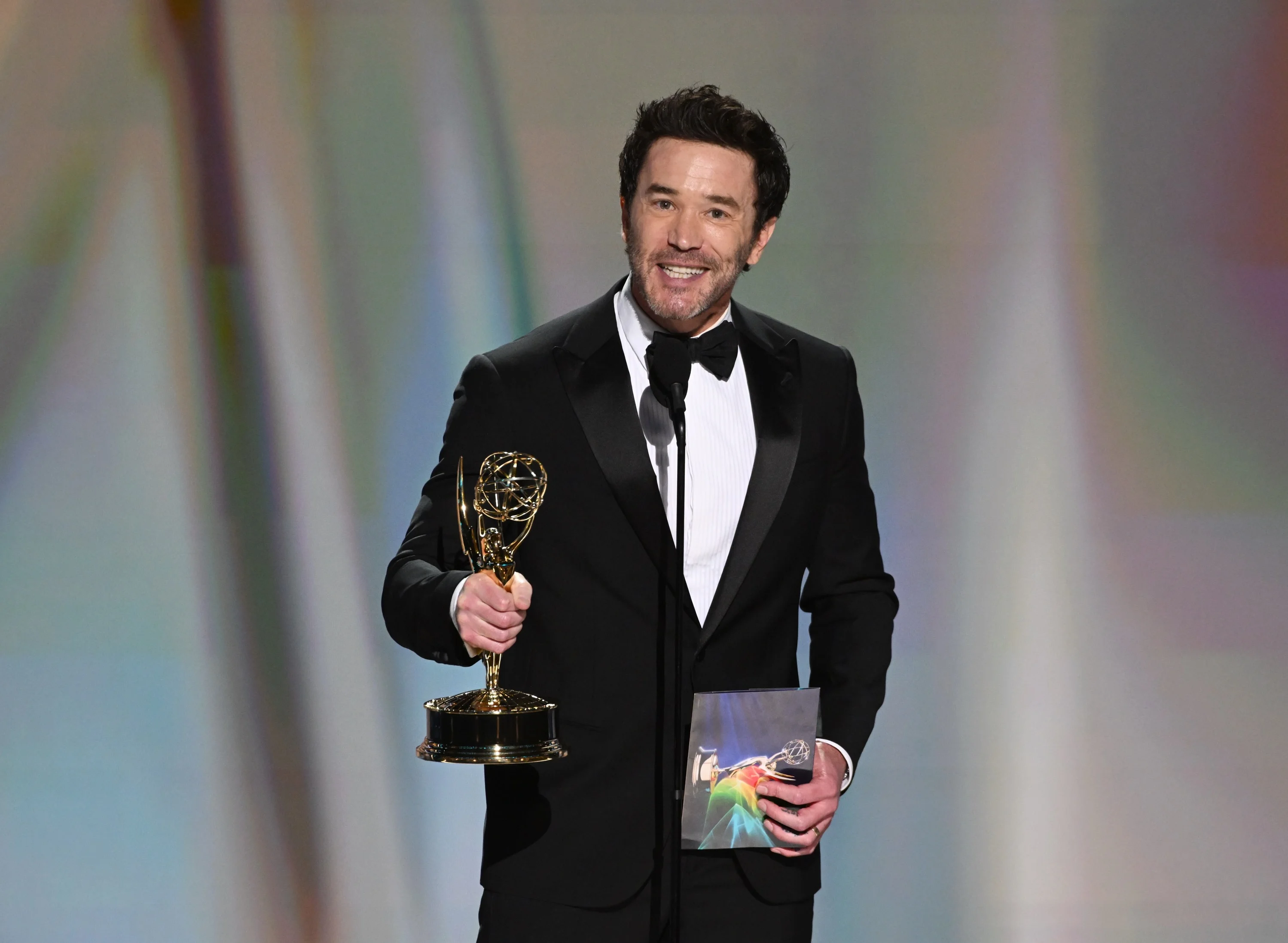 Rob McElhenney holding Emmy statuette smiling broadly in black tie