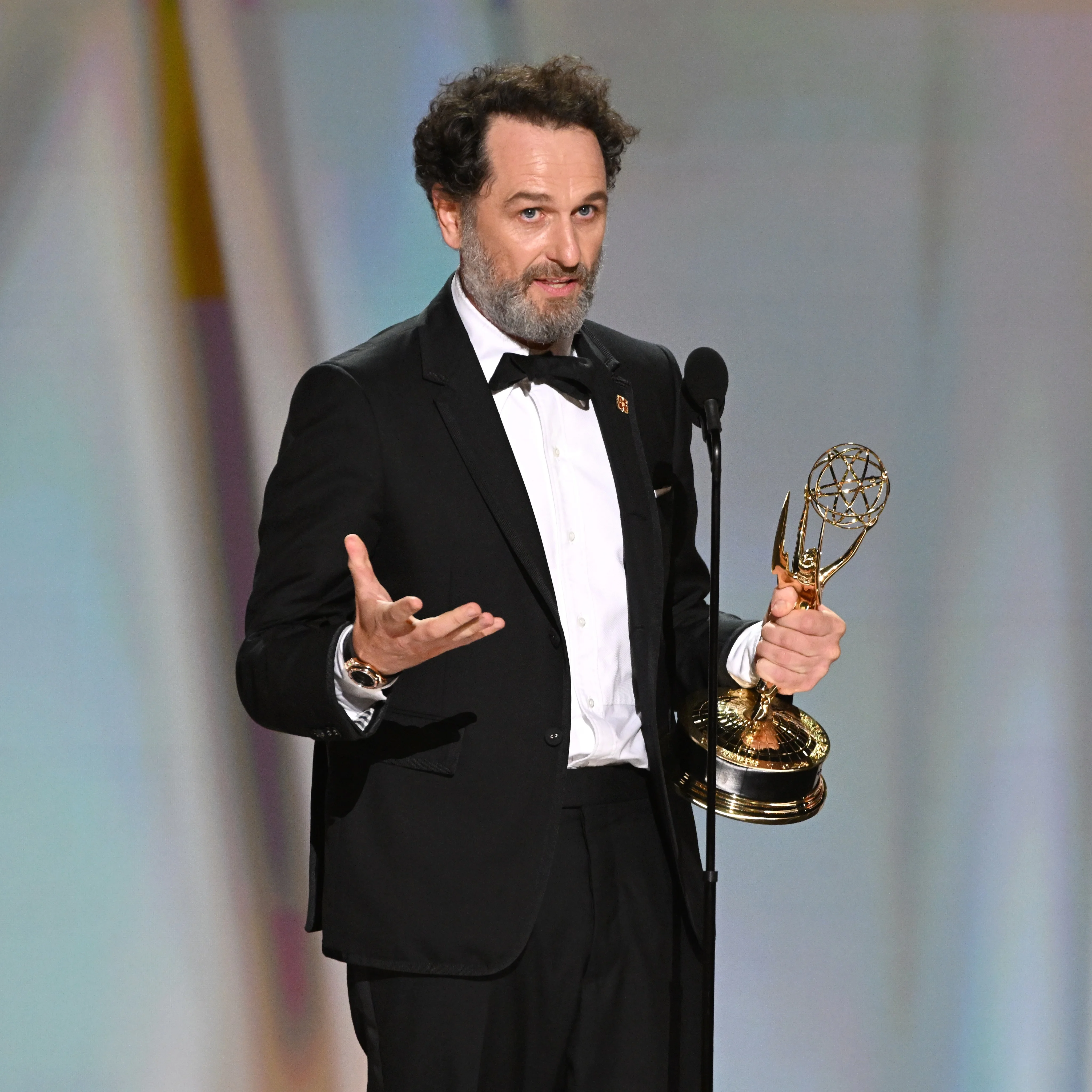 Director holding Emmy gesturing passionately during backstage interview
