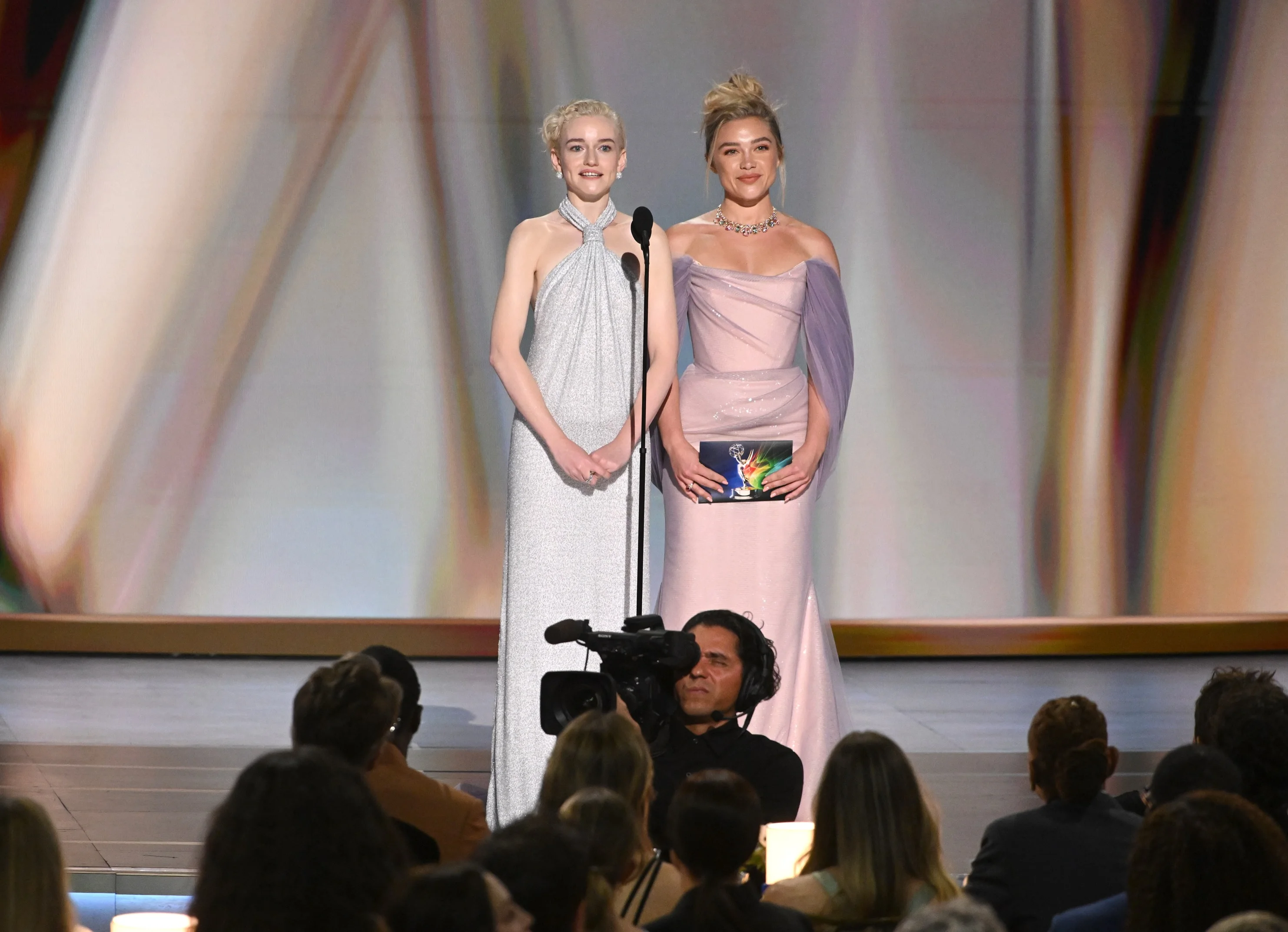 Dakota Fanning and Elle Fanning presenting together on stage in harmonious pastel gowns