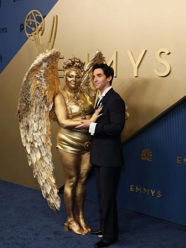 Star posing proudly alongside the colossal golden Emmy winged sculpture